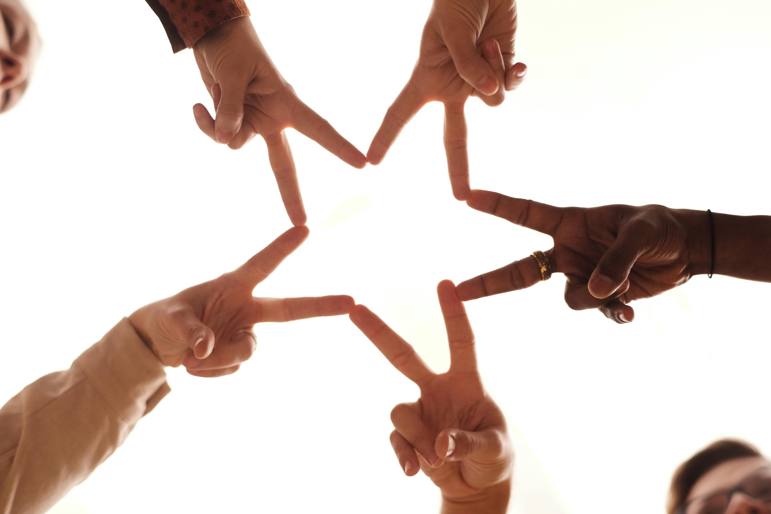 A group of diverse hands forming a star shape, symbolizing unity and friendship.